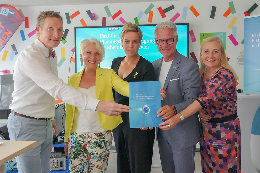 Fünf Personen stehen nebeneinander und halten eine Broschüre in den Händen.