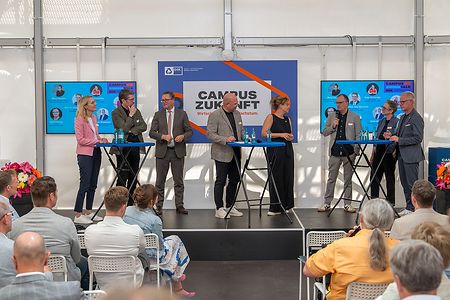 Acht Personen stehen auf einem Podium 